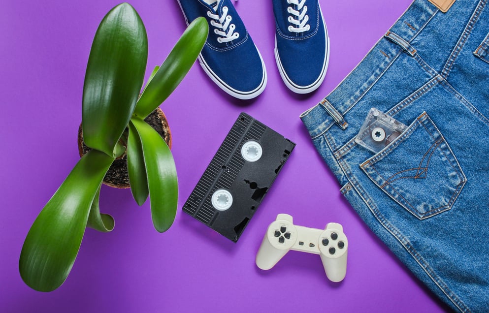 Casual women's retro style denim skirt, video cassette, gamepad, sneakers shoes, pot with a green plant on purple background. Pop culture, Minimalism