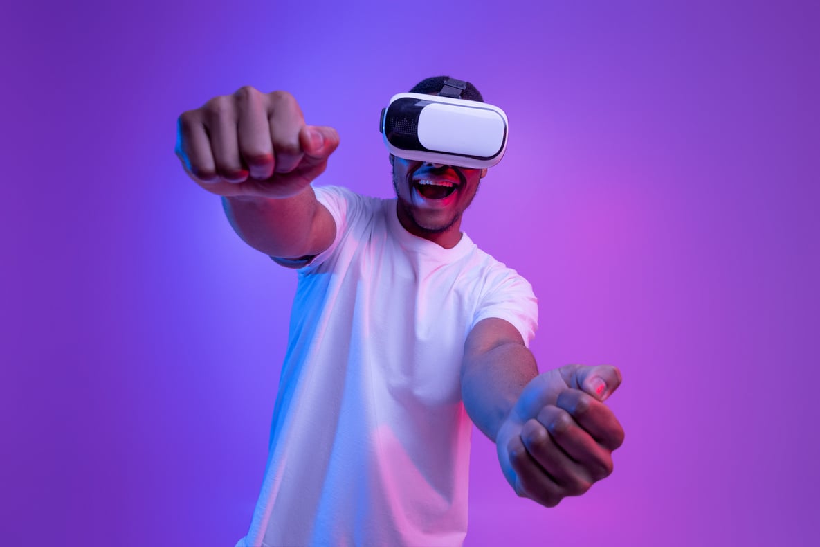 Young african american man playing video games in VR-glasses under purple neon light